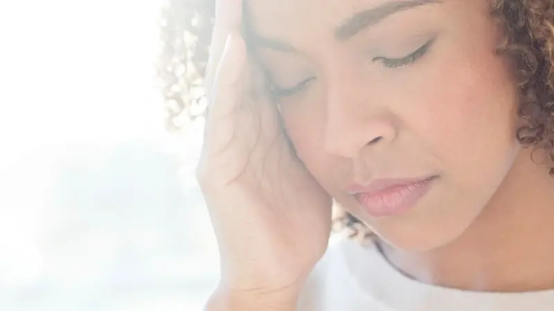 Woman with hands over her suffering with migraine