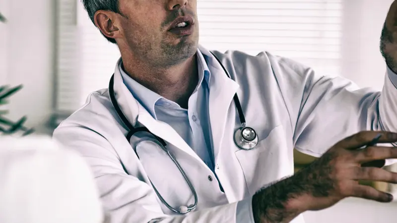 Doctor showing woman part of spine in clinic.