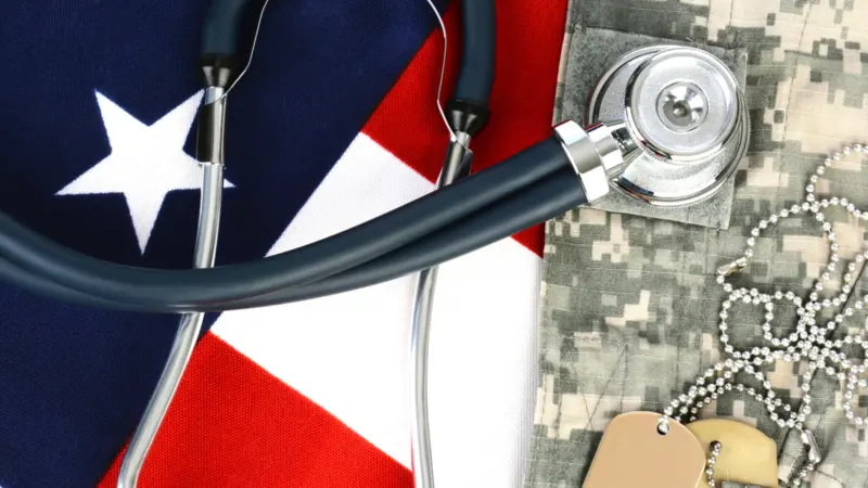 Military fatigues and dog tags on an American Flag with a stethoscope to illustrate health care in the armed services