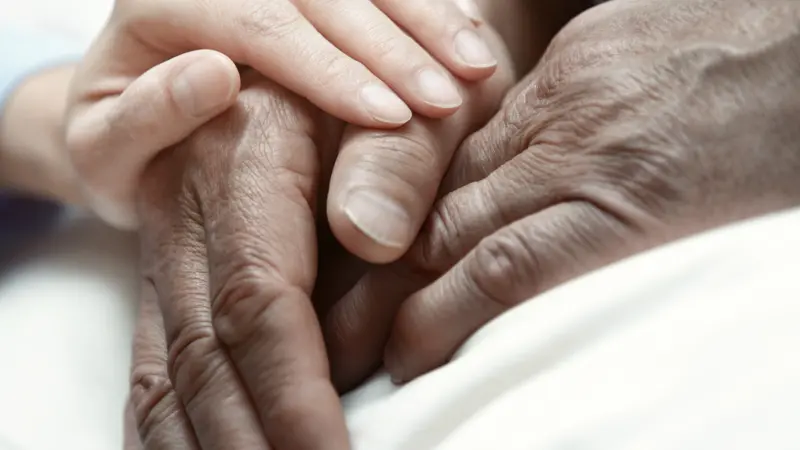 Hand of woman touching senior man in clinic