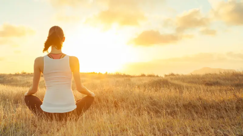 Woman meditating against a beautiful sunset.