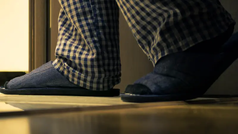 Adult man in pajamas walks to a bathroom at the night