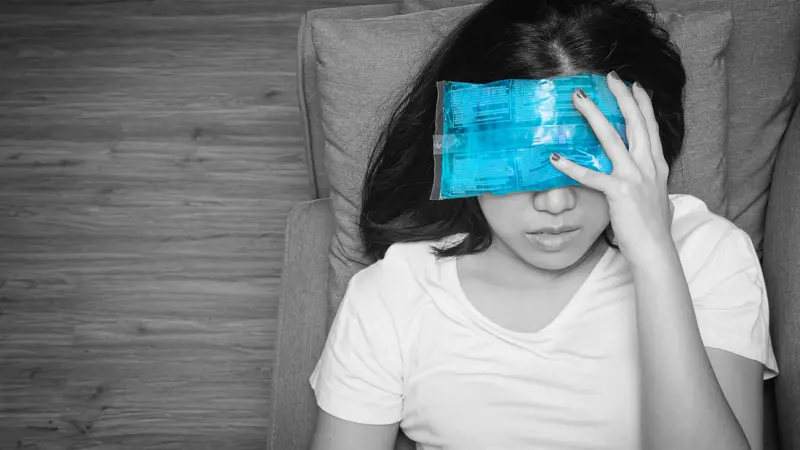 woman with cold pack on her forehead for relief headaches and migraines, black and white tone