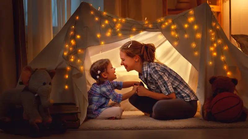  mother and daughter playing at home in a tent