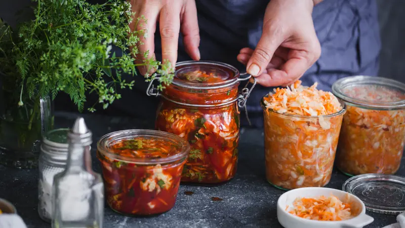 Fermented preserved vegetables food concept. Cabbage kimchi and sauerkraut sour cabbage glass jars, over rustic blue table