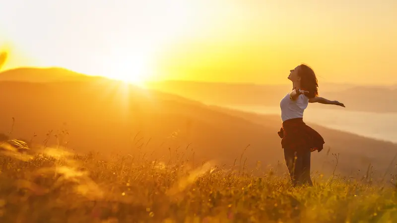 Happy woman on the sunset in nature in summer with open hands