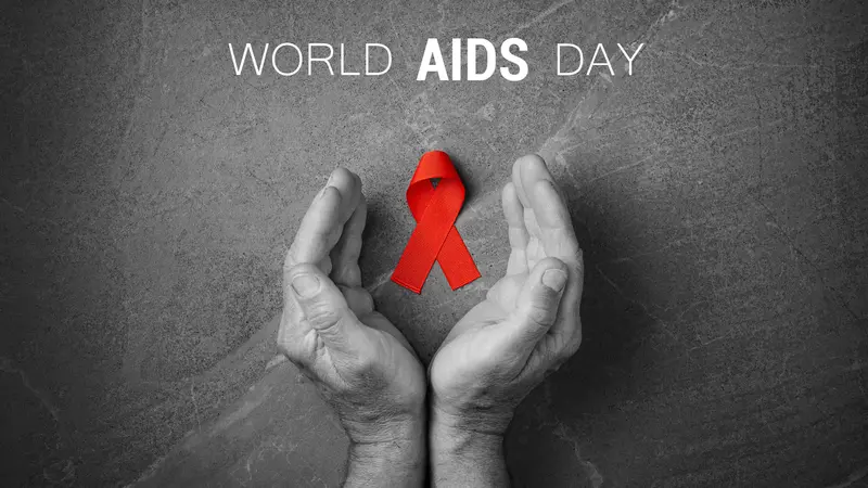 Red ribbon in hands on gray background, World AIDS Day, symbol of fight against HIV and AIDS