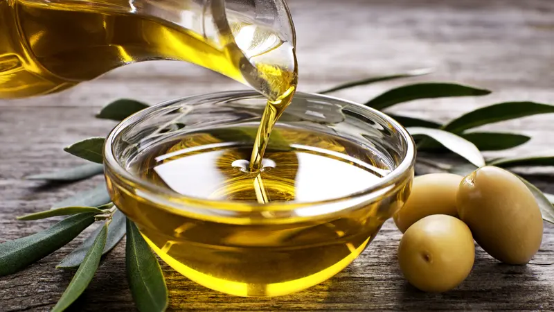 Bottle pouring virgin olive oil in a bowl close up