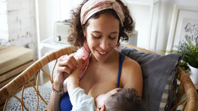 Young mixed race mother enjoying intimate moment with her baby son while breastfeeding him