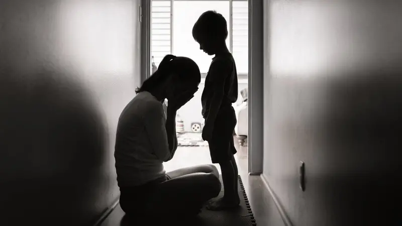 Depressed mother crying next to her child.