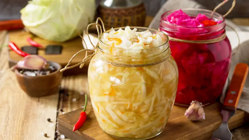 Homemade Sauerkraut with Carrot and Salad Cabbage with Beetroot on a wooden table.