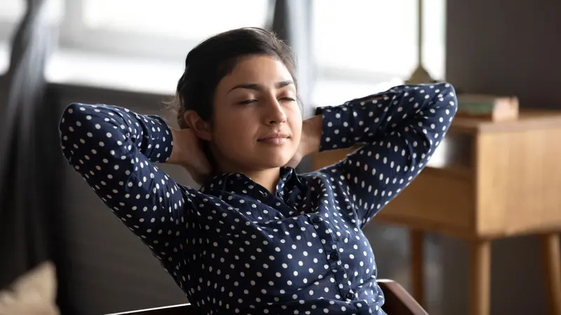 Calm relaxed Indian lady practicing breath work at home office