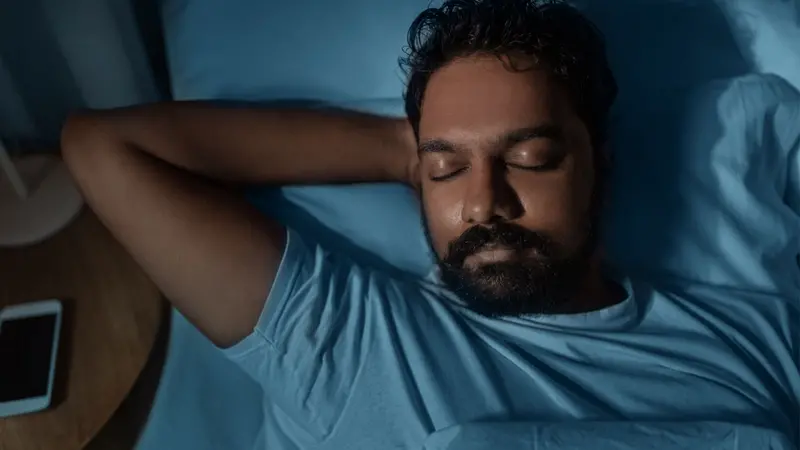 Indian man sleeping in bed at home at night