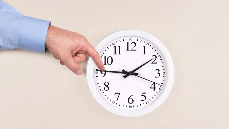 A man uses his finger to push back the time on a clock