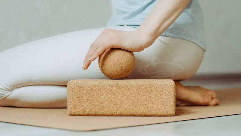 Side view of person doing palmar fascia release with a large cork ball on a cork block