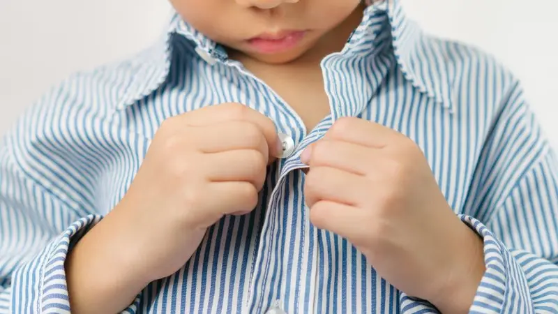 Close up of a little kindergarten boy's hands learning to get dressed