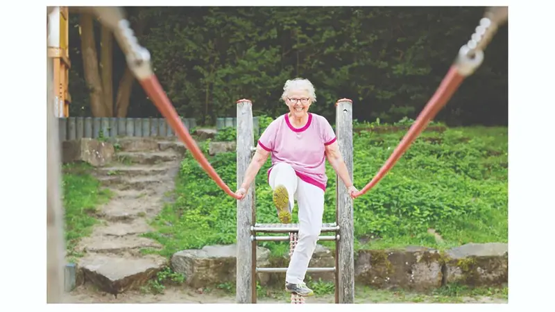 Older woman walking across a rope bridge