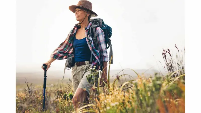 Senior woman on a hiking trip with the help of a trekking pole.