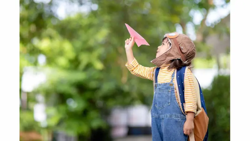 Little boy flying a paper airplane