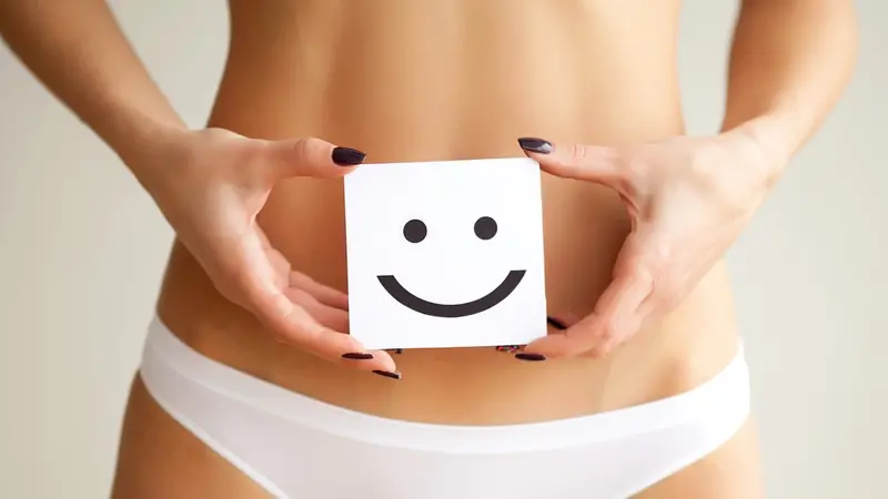 Woman holding paper with smile mark over her stomach