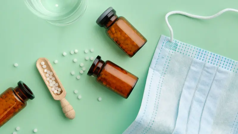 Bottles of homeopathic granules, water glass for preparation of medicinal solution, protective medical mask