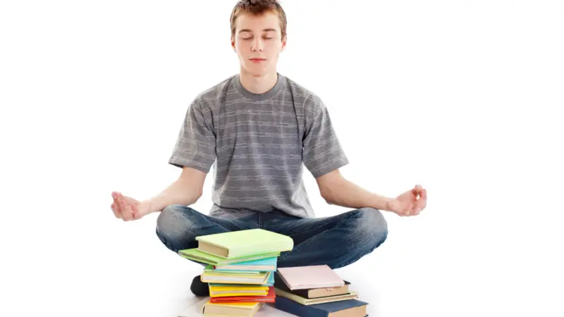 Teenager meditating with his books