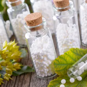 Homeopathic lactose sugar globules in glass bottles with plants