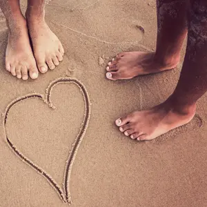 Racially diverse children's feet at the beach with a heart drawn