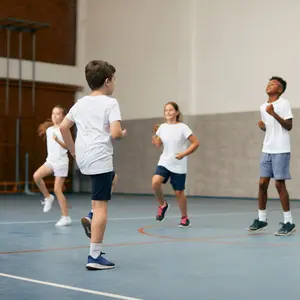 Group of elementary students having PE class with their sports teacher at school gym