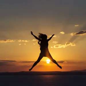 Woman jumping for joy and happines at sunset