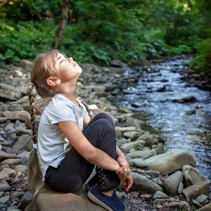 Girl sitting on side of a stream
