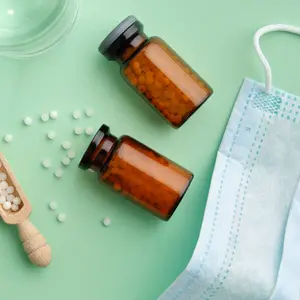 Bottles of homeopathic granules, water glass for preparation of medicinal solution, protective medical mask