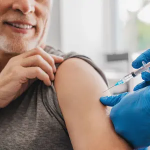 Doctor making injection to senior patient in clinic Doctor making injection to senior patient in clinic