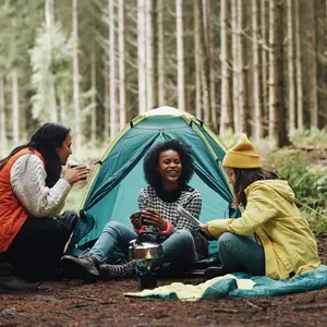 Smiling group of young female friends sitting at their forest campsite  Smiling group of young female friends sitting at their forest campsite