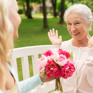 Woman presenting bouquet of flowers to older woman Woman presenting bouquet of flowers to older woman