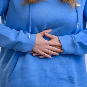 Woman holding her stomach feeling pain and discomfort Woman holding her stomach feeling pain and discomfort