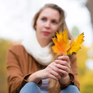 Woman holding golden maple leaves Woman holding golden maple leaves